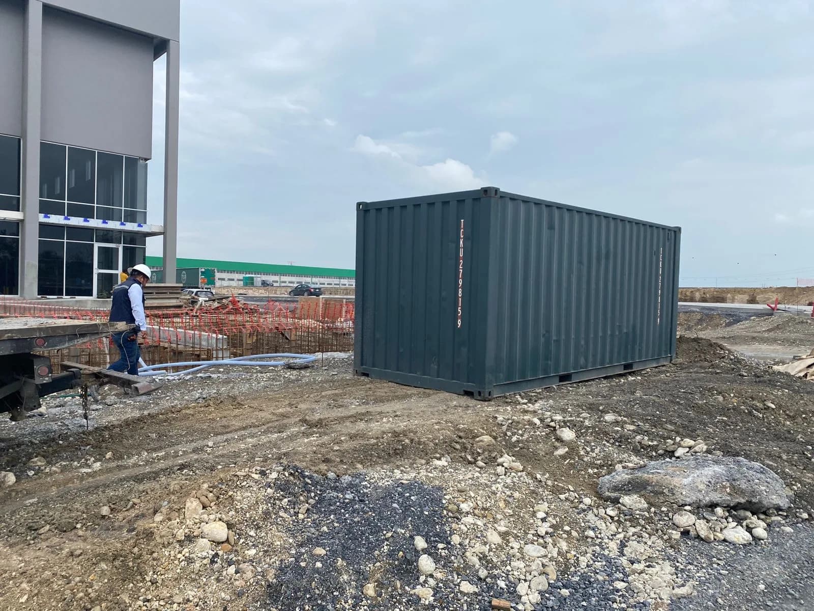 Contenedor marítimo abierto en obra de construcción con materiales almacenados