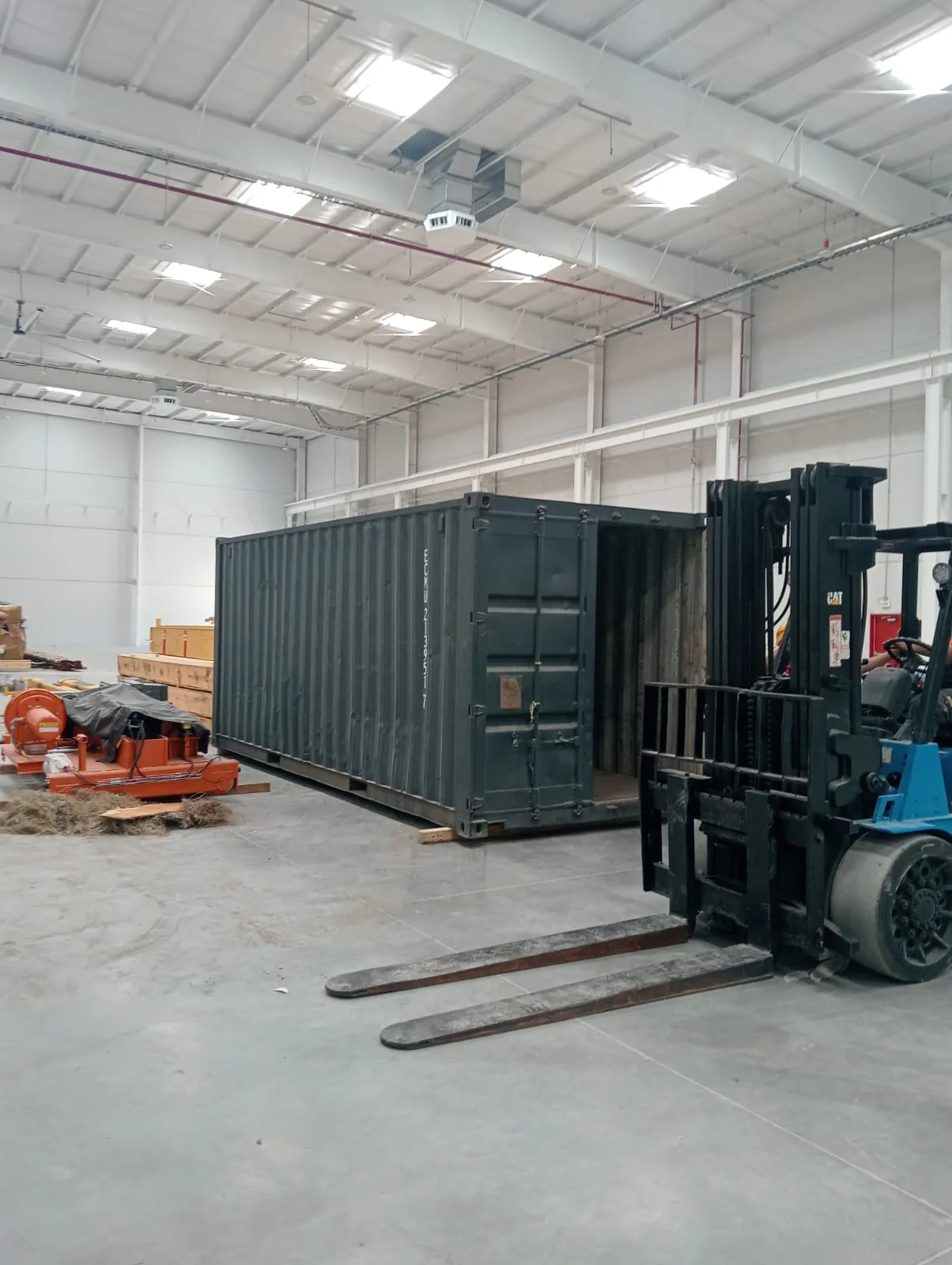 Contenedor dentro de nave industrial con montacargas